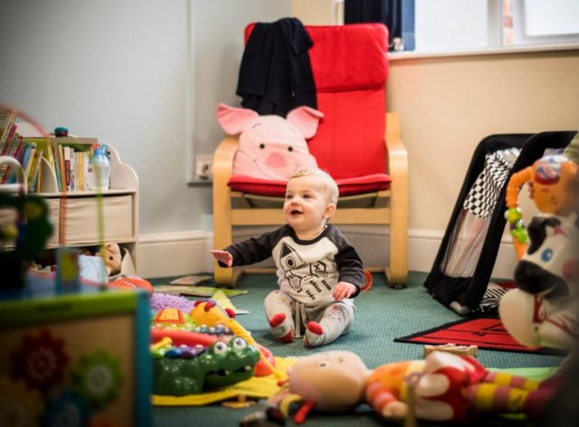 A baby having fun in the nursery surrounded by toys