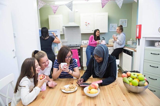 Girls relaxing and talking in their boarding house kitchen