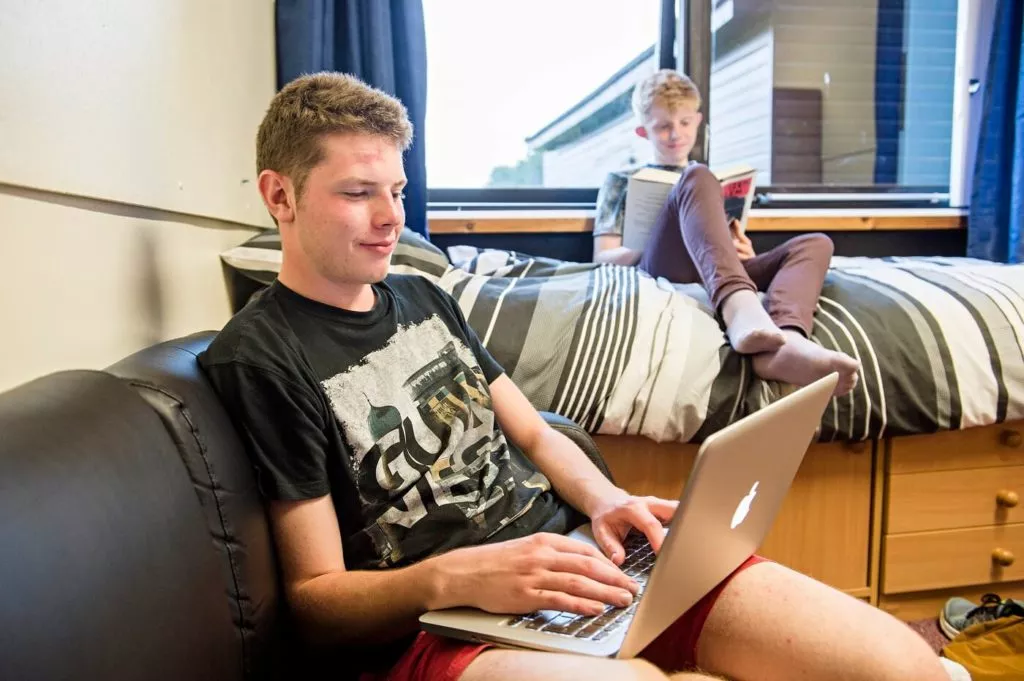 Two male pupils revising in their boarding house bedroom.