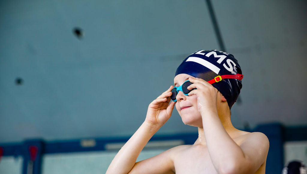 Young child wearing swimming hat and goggles
