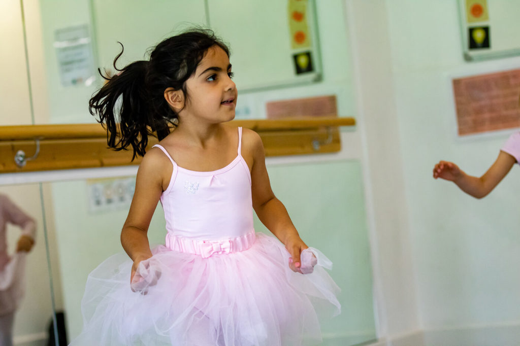 Young primary school girl dancing in a pink tutu
