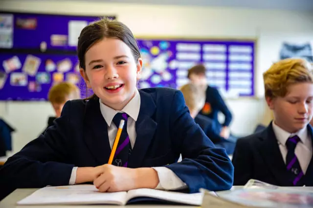 A girl smiling as she completes her academic work in the classroom