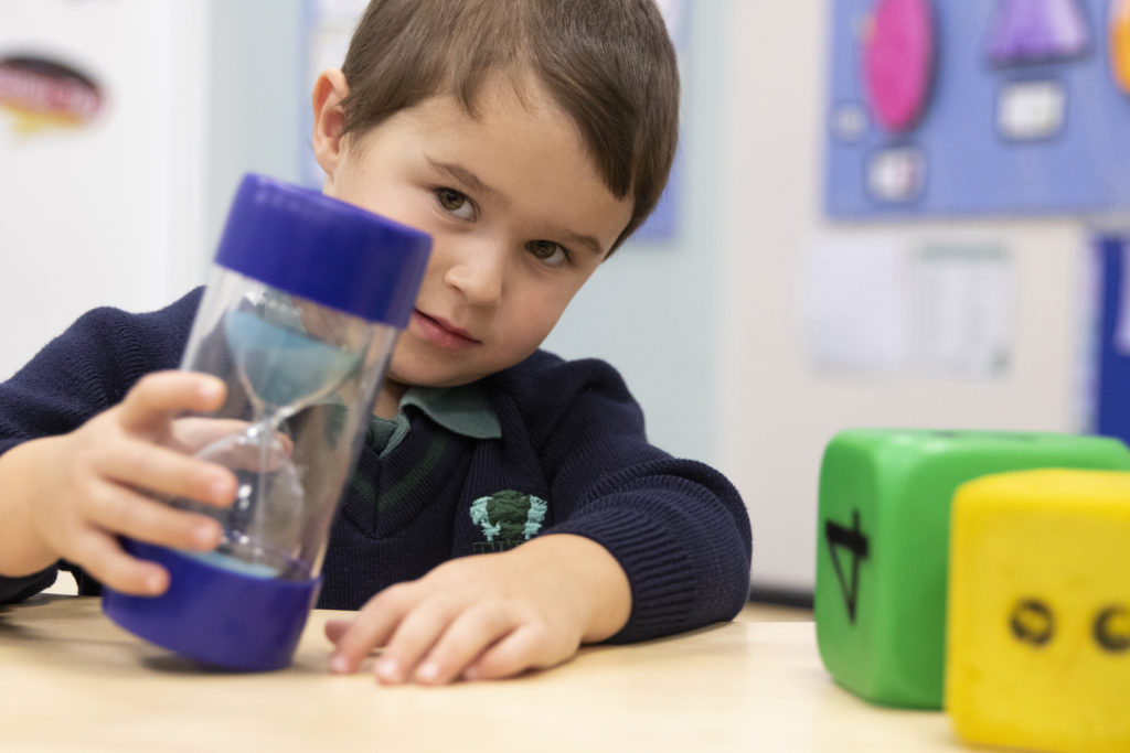 Pre-school child playing with a toy sand timer at The Elms private day nursery and pre-school