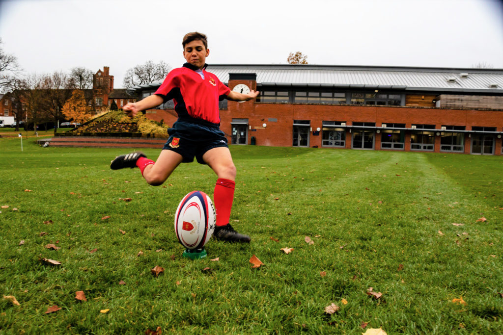 Young boy kicking a rugby ball