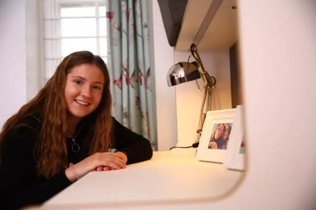 sixth form girl sat at a desk smiling