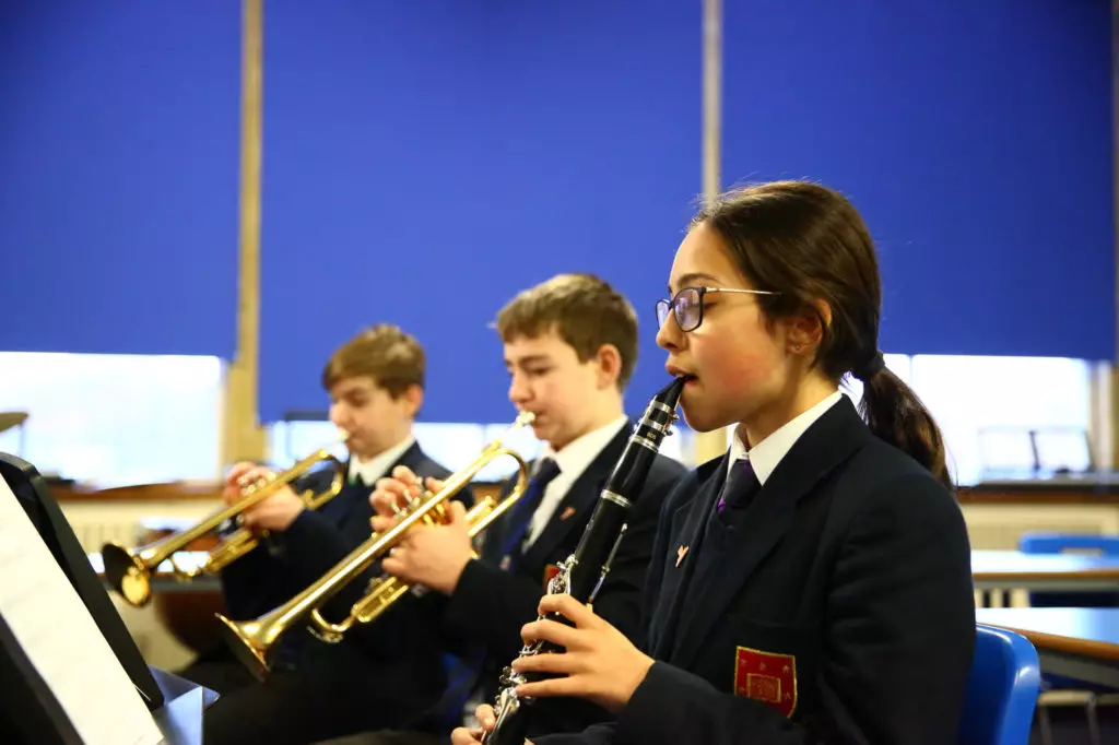 Young girl playing the clarinet and two young boys playing the trumpet