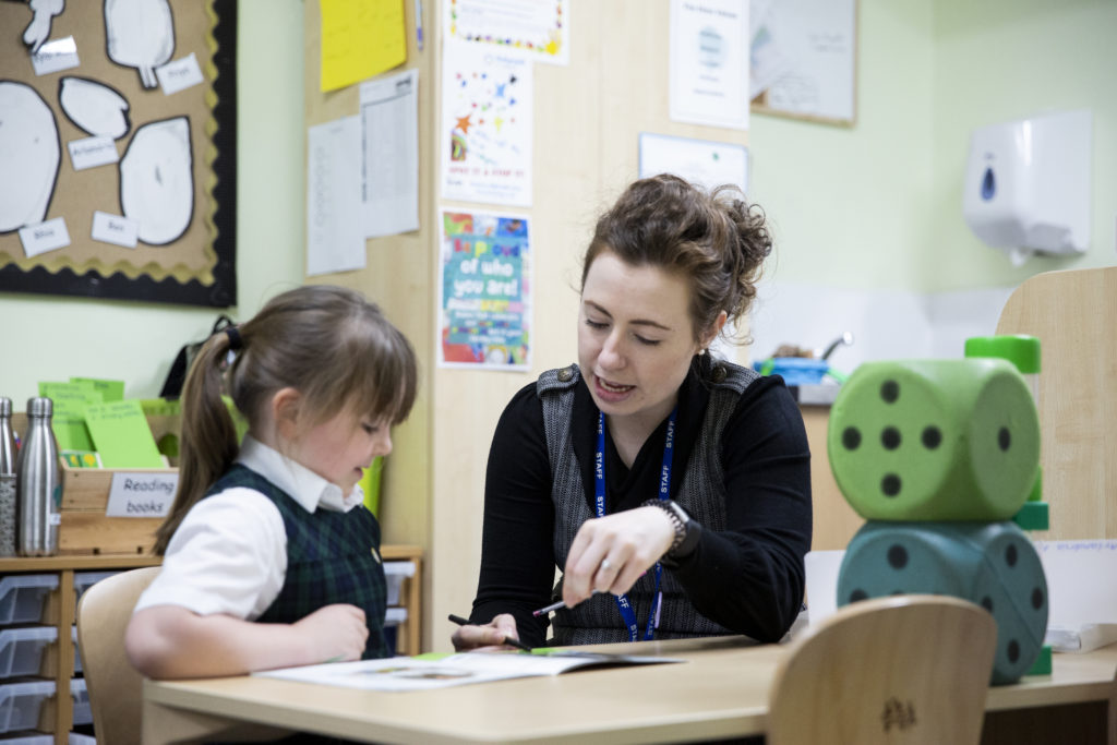 Primary School teacher sat with young pupil talking