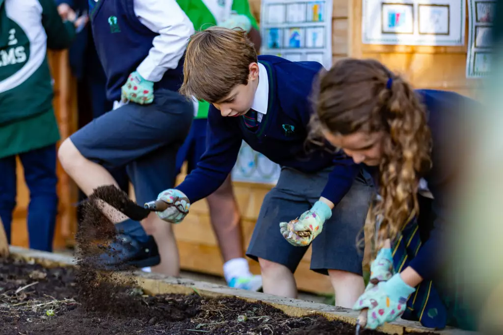 Primary school children learning how to maintain a wild garden using hand tools at The Elms Nursery and Junior School