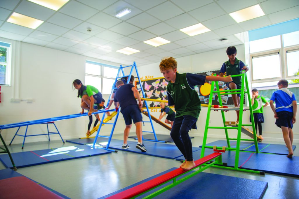 Young children taking part in PE lesson in activity hall