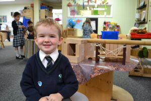 A Reception child sitting in front of block bridge