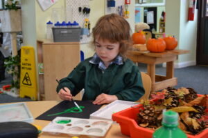 A Reception child enjoying Autumnal painting